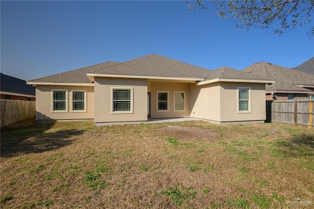 rear view of property with a fenced backyard, a yard, and stucco siding