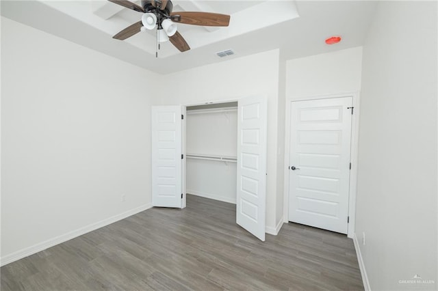 unfurnished bedroom featuring baseboards, a closet, visible vents, and wood finished floors