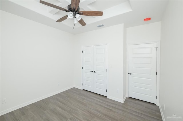 unfurnished bedroom featuring baseboards, visible vents, a ceiling fan, wood finished floors, and a closet