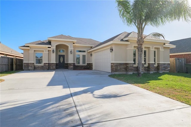 prairie-style house with driveway, stone siding, an attached garage, fence, and stucco siding