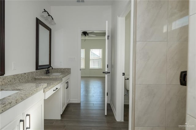 bathroom with a sink, a ceiling fan, visible vents, wood tiled floor, and double vanity