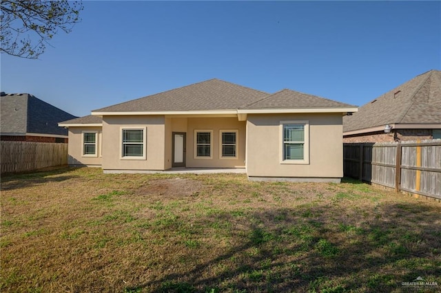 back of house with a shingled roof, a fenced backyard, a yard, a patio area, and stucco siding