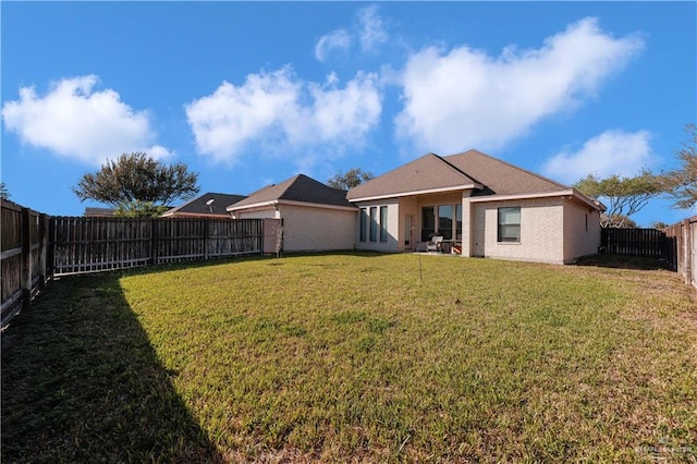 rear view of property with a yard and a fenced backyard