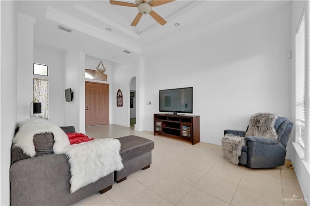 living room with visible vents, a tray ceiling, light tile patterned floors, a towering ceiling, and arched walkways