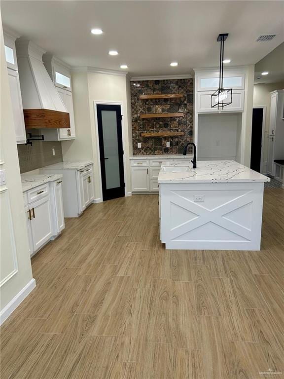 kitchen featuring visible vents, custom range hood, and white cabinets