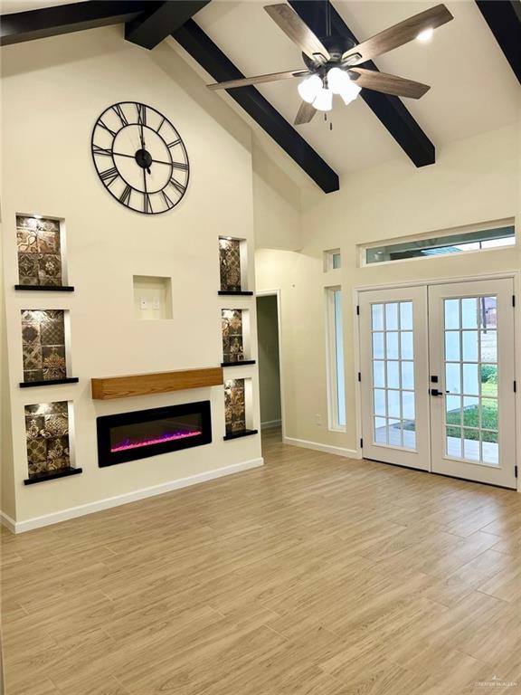 unfurnished living room featuring beam ceiling, a glass covered fireplace, and high vaulted ceiling