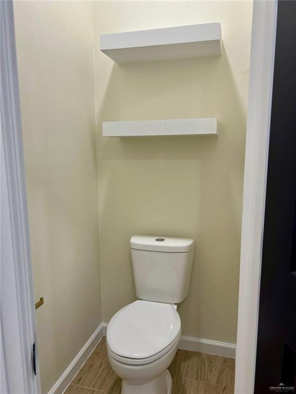 bathroom with wood finished floors, toilet, and baseboards
