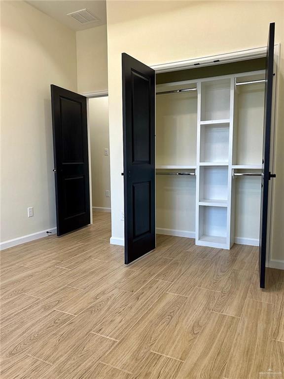 unfurnished bedroom featuring light wood-style floors, a closet, visible vents, and baseboards