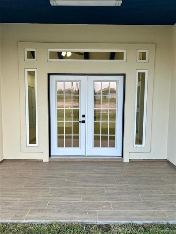 doorway to property featuring a deck, stucco siding, and french doors