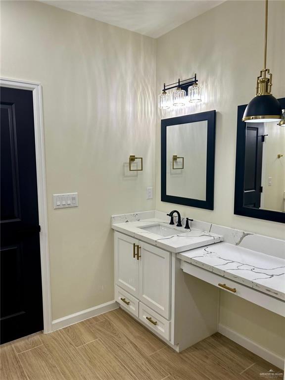 bathroom featuring baseboards, wood finished floors, and vanity
