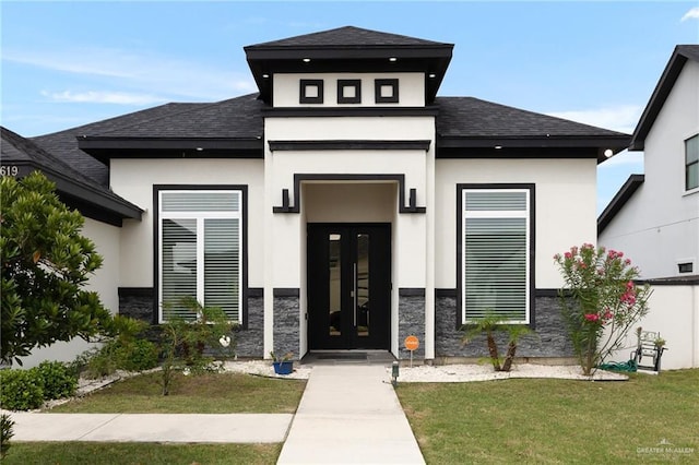 view of front facade featuring a front yard, stucco siding, and roof with shingles