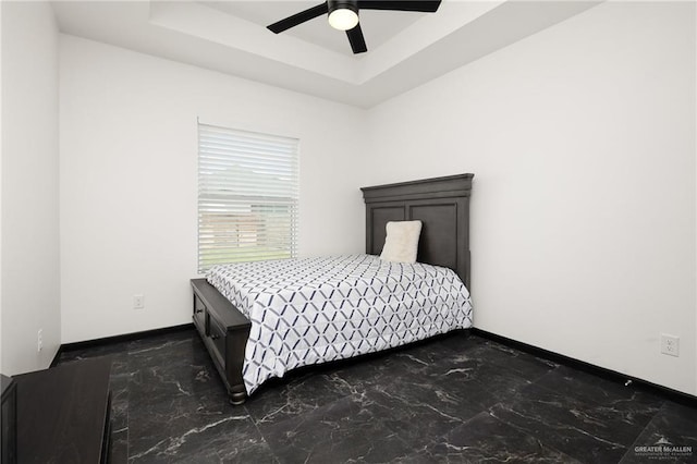 bedroom with a tray ceiling, baseboards, marble finish floor, and a ceiling fan