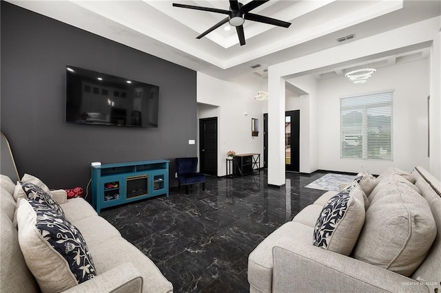 living room with baseboards, a raised ceiling, marble finish floor, visible vents, and a ceiling fan