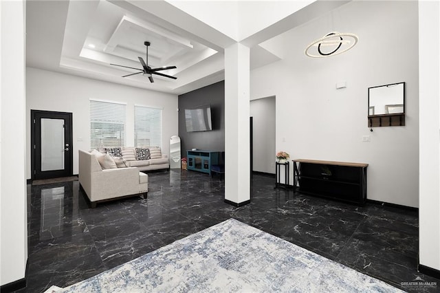 living room with marble finish floor, a raised ceiling, baseboards, and ceiling fan