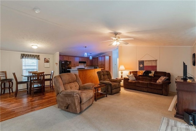 carpeted living room with ceiling fan, vaulted ceiling, and ornamental molding