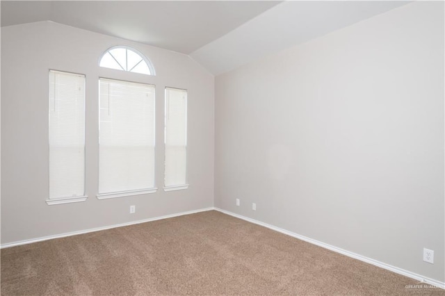 carpeted empty room with vaulted ceiling