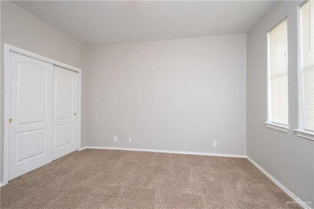 unfurnished bedroom with light carpet and a closet