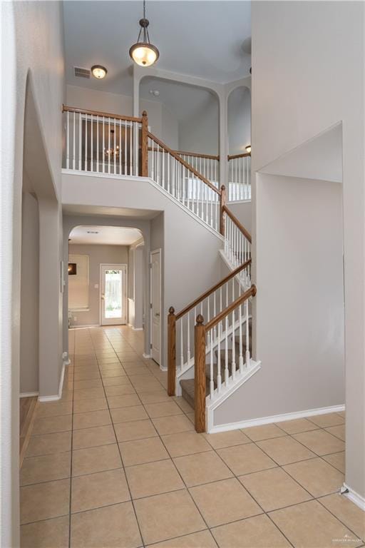 stairs featuring tile patterned flooring and a high ceiling