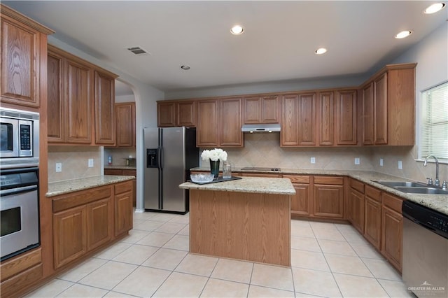 kitchen with appliances with stainless steel finishes, sink, a kitchen island, and light tile patterned floors