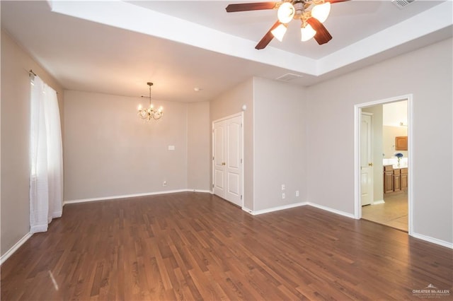 spare room with ceiling fan with notable chandelier, dark hardwood / wood-style flooring, and a tray ceiling