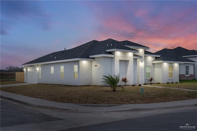 view of front of home featuring a garage, driveway, a shingled roof, and stucco siding