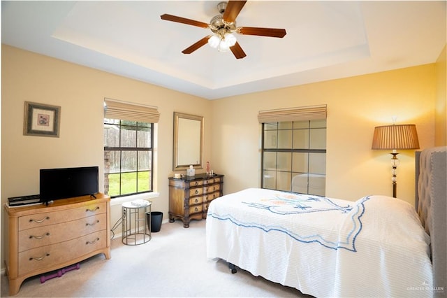 bedroom featuring carpet, a tray ceiling, and ceiling fan