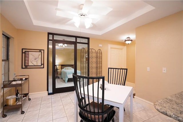 dining space featuring light tile patterned floors, a raised ceiling, and ceiling fan