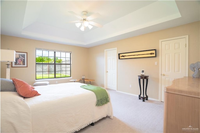 bedroom featuring ceiling fan, a raised ceiling, and carpet floors