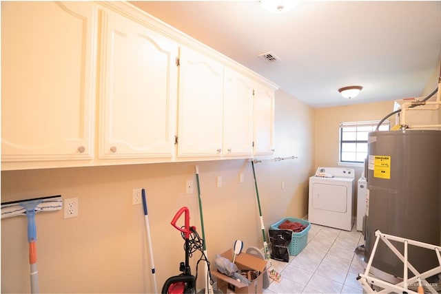 clothes washing area featuring washing machine and dryer, water heater, light tile patterned floors, and cabinets