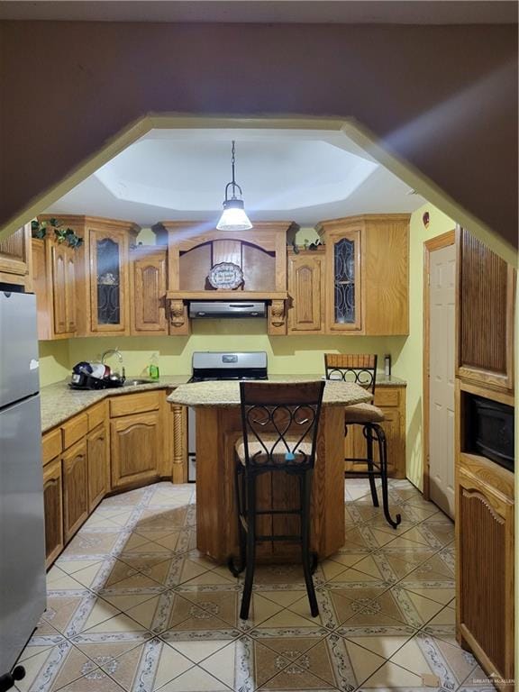 kitchen with gas stove, a center island, stainless steel fridge, pendant lighting, and a breakfast bar