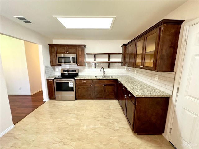 kitchen featuring sink, light stone counters, decorative backsplash, appliances with stainless steel finishes, and light wood-type flooring