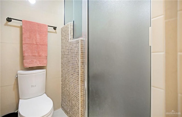 full bath featuring a shower stall, toilet, and tile walls