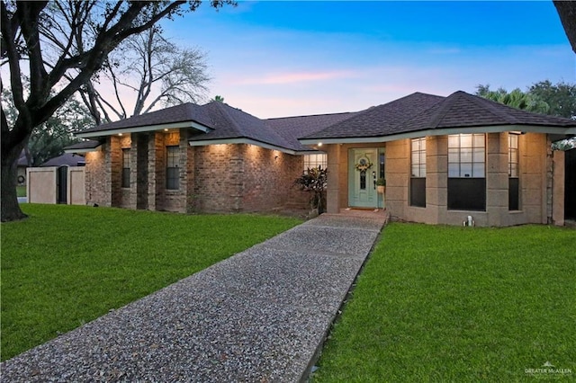 view of front of home featuring brick siding, a front lawn, and roof with shingles