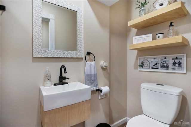 bathroom with toilet, baseboards, and vanity