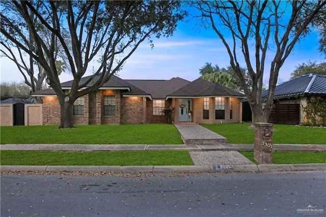 view of front of property featuring fence, a front lawn, and brick siding