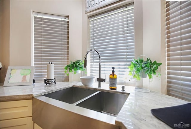 kitchen with a healthy amount of sunlight, a sink, and light stone countertops