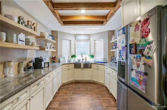 kitchen with light stone countertops, wood tiled floor, stainless steel refrigerator with ice dispenser, open shelves, and a sink