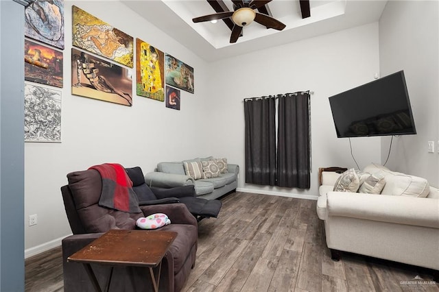 living room featuring hardwood / wood-style flooring, ceiling fan, and a raised ceiling