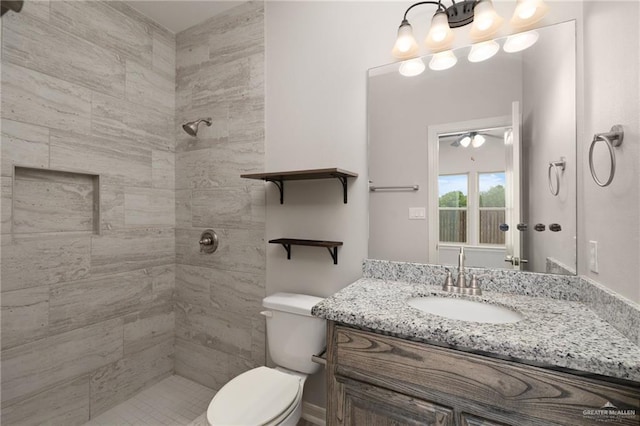 full bathroom with tiled shower, vanity, and toilet