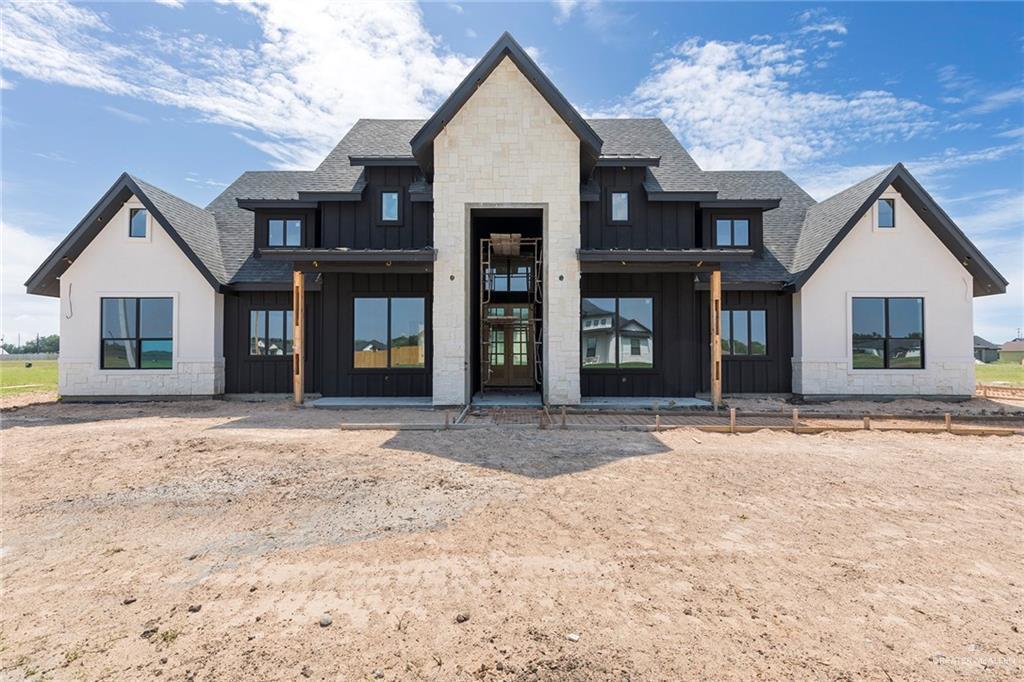 5413 Jay Ln, Weslaco, TX 78599 - back of property with board and batten siding, a shingled roof, and stone siding
