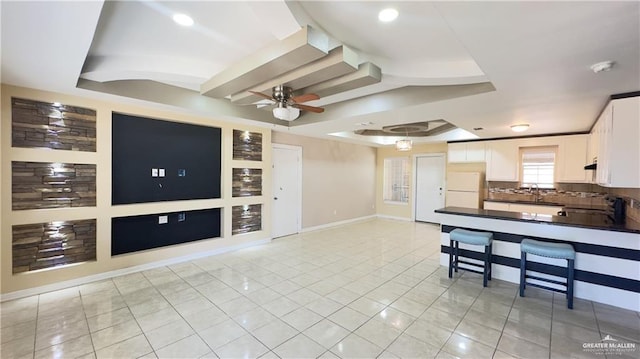 kitchen featuring a tray ceiling, dark countertops, decorative backsplash, freestanding refrigerator, and white cabinetry