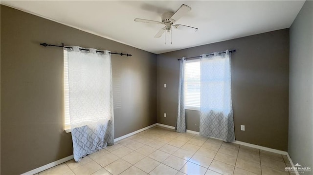 tiled empty room featuring ceiling fan and baseboards