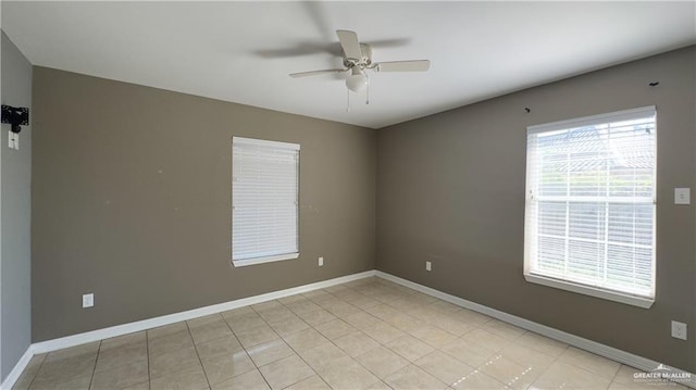 spare room with a ceiling fan, light tile patterned flooring, and baseboards