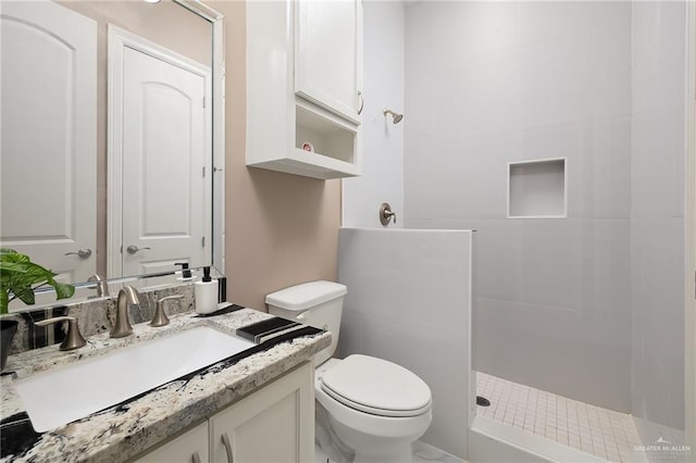 full bathroom with toilet, vanity, and a tile shower