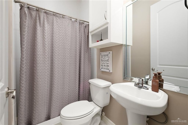 bathroom with a shower with shower curtain, toilet, and a sink