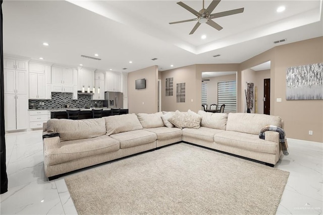 living room with recessed lighting, visible vents, a raised ceiling, and marble finish floor