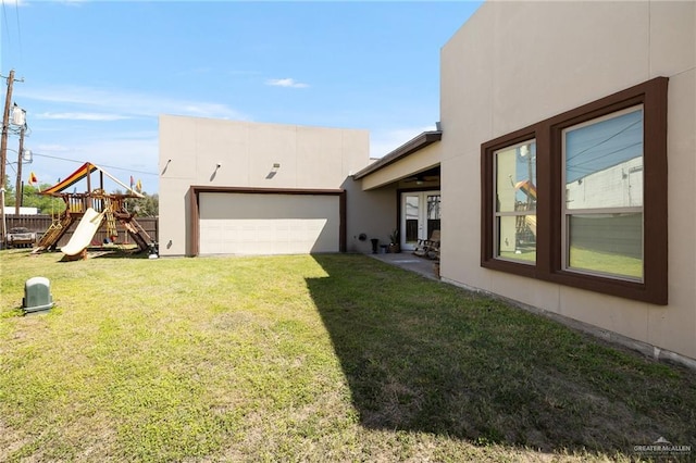 view of yard featuring driveway, a playground, and a garage