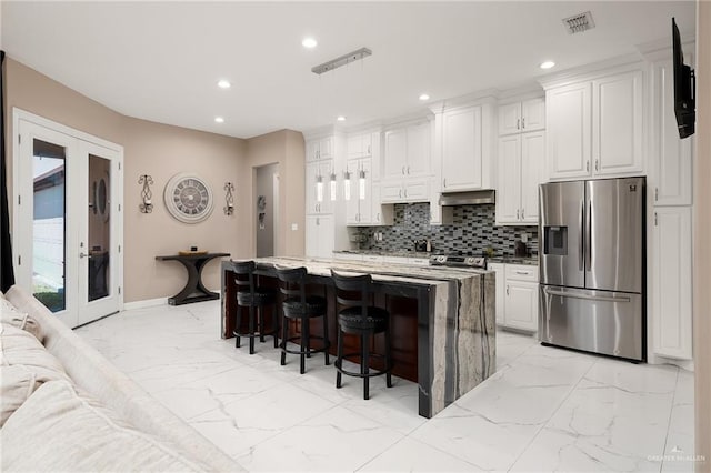 kitchen with marble finish floor, a kitchen breakfast bar, tasteful backsplash, french doors, and appliances with stainless steel finishes