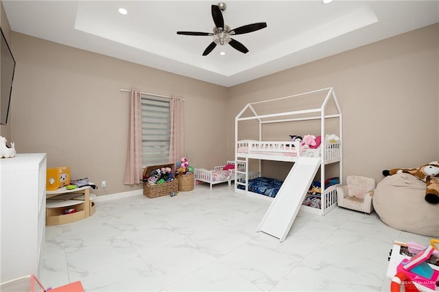 bedroom with recessed lighting, marble finish floor, and a tray ceiling