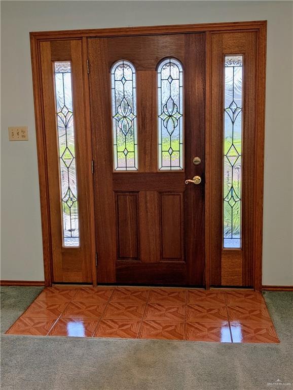 carpeted foyer featuring baseboards